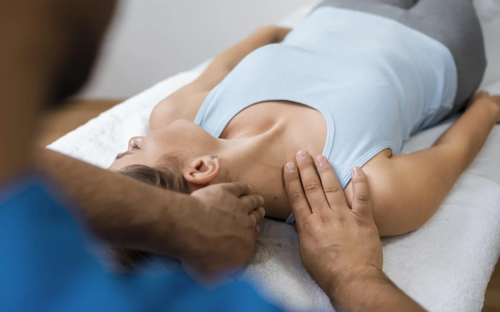 Fizjoterapeuta pracuje z karkiem i barkiem pacjentki leżącej na plecach
