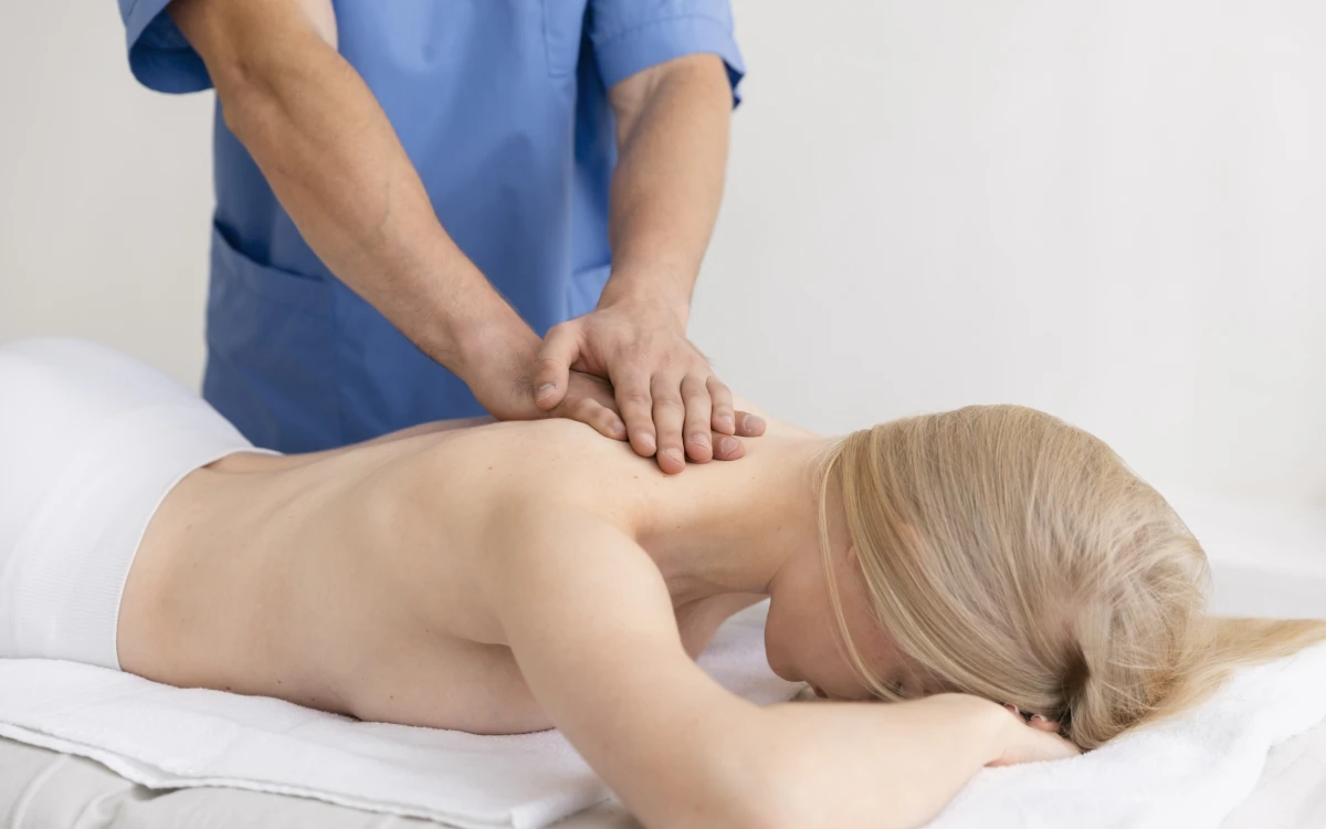 Fizjoterapeuta rozluźnia mięśnie karku i barków pacjentki leżącej na kozetce
